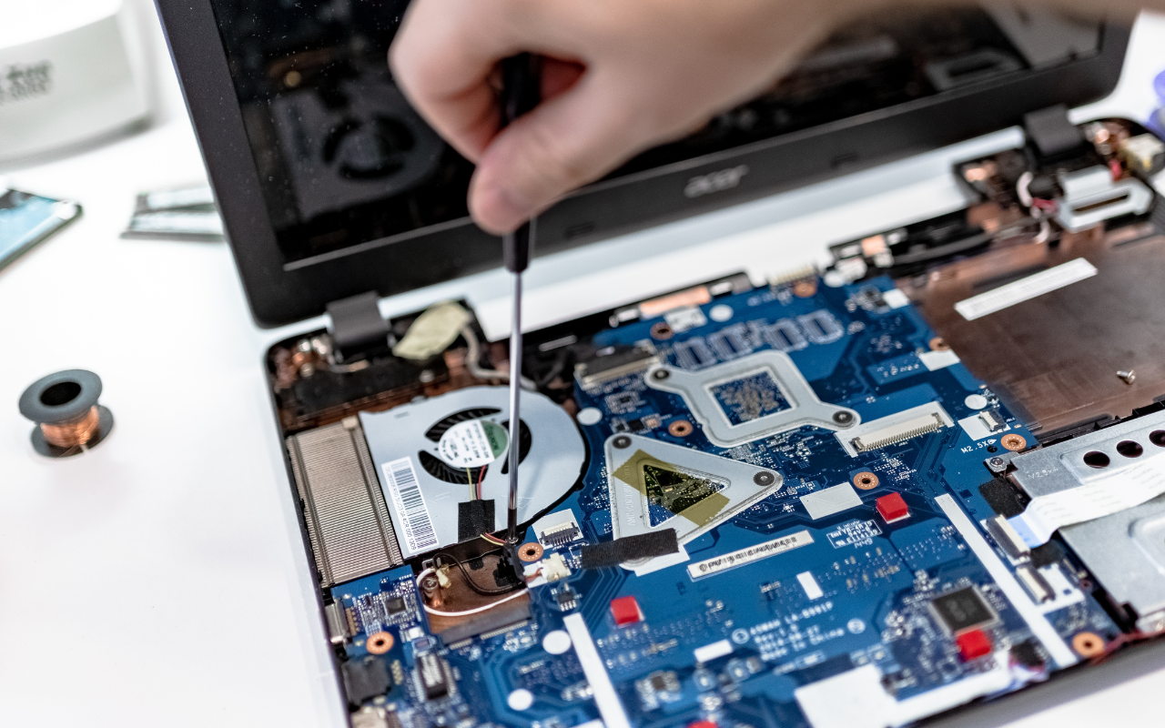 Person using tools to open a laptop for repair at home